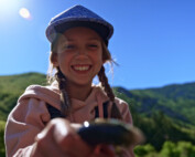 A young girl holds a trout while smiling