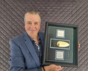Patrick Campeau stands holding a plaque and award.